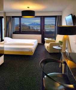 ツークにあるGuggital Hotel Restaurantのベッドと大きな窓が備わるホテルルームです。