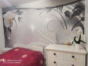 1 dormitorio con 1 cama y una pared con flores en Chambre d hôte à 20 min de VERSAILLES, en Le Mesnil-Saint-Denis