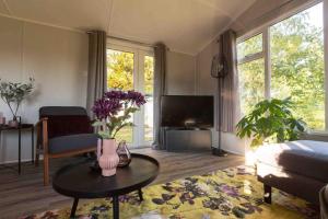 a living room with a table and a tv at 6-persoons chalet in Voorthuizen op de Veluwe in Voorthuizen