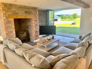 a living room with a large couch and a fireplace at Coed farm-hot tub-sleeps 12-near Brecon in Brecon