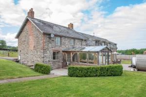 an old stone house with a greenhouse in the yard at Coed farm-hot tub-sleeps 12-near Brecon in Brecon