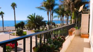 a balcony with a view of the beach and palm trees at Beach panorama Caleta in Caleta De Velez