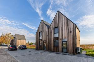 una casa de madera con un coche aparcado en un aparcamiento en Kopų ramybė, en Palanga