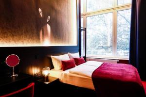 Schlafzimmer mit einem Bett mit roten Kissen und einem Fenster in der Unterkunft Sleephotels Casino in Hamburg