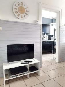 ein Wohnzimmer mit einem TV und einer Uhr an der Wand in der Unterkunft Bienvenue chez vous ! Malo (3mn de la plage) in Dunkerque