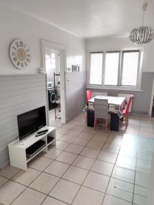 uma sala de estar com piso em azulejo, uma televisão e uma mesa em Bienvenue chez vous ! Malo (3mn de la plage) em Dunkerque