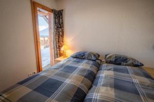 two beds sitting next to a window in a bedroom at La vue du Roi - Detached chalet (6p). 3 bedrooms and 2 bathrooms. In the centre of Vallandry, with a beautiful view in Landry