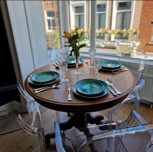una mesa con platos y vasos y un jarrón de flores en De Cosy Barock met gezellige Patio !, en Breda