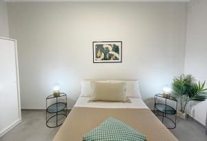 een witte slaapkamer met een bed en twee kaarsen bij Casa Lulu in Belpasso