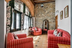 a living room with red chairs and a stone wall at Rokeby Manor in Mussoorie