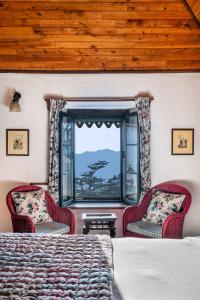 a bedroom with two chairs and a bed and a window at Rokeby Manor in Mussoorie
