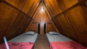 Cette chambre est dotée de 2 lits dans un mur en bois. dans l'établissement Sandhya Giri Beach Resort, à Brono