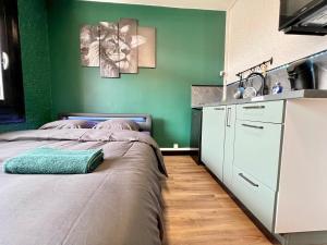 sypialnia z dwoma łóżkami i zieloną ścianą w obiekcie Magnifique studio ~Hipster~ porte du Futuroscope w mieście Chasseneuil-du-Poitou