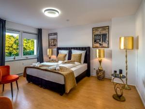 ein Schlafzimmer mit einem großen Bett und zwei Fenstern in der Unterkunft JUNIK Apartments "Am Sternbuschweg" in Duisburg