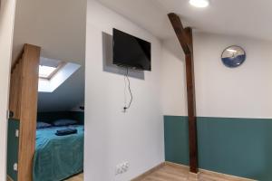 a bedroom with a bed and a tv on the wall at Uroczy, przytulny apartament poddasze in Radom
