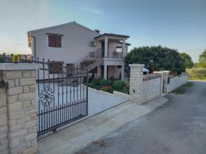 une maison blanche avec un portail et une clôture dans l'établissement Apartmani Bernarda, à Poreč