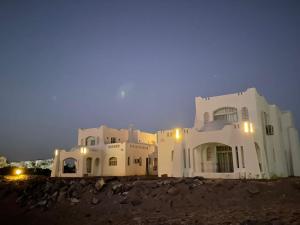 Un grand bâtiment blanc avec des lumières allumées la nuit dans l'établissement The white villas (TWV), à Ras Sudr