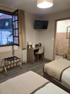 a hotel room with two beds and a desk and a television at Au Lion d'or in Saint-Pol-sur-Ternoise