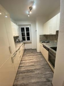 una cucina con armadietti bianchi e pavimenti in legno di Gemütliche Wohnung in zentraler Lage a Graz