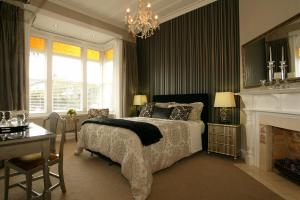 um quarto com uma cama, uma lareira e um lustre em Eden Park Bed And Breakfast Inn em Auckland