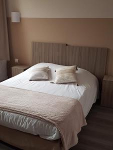 a large white bed with two pillows on it at Au Lion d'or in Saint-Pol-sur-Ternoise