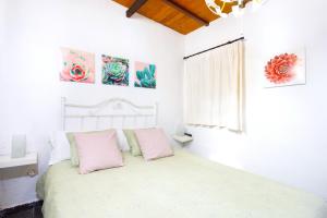 a white bedroom with a bed with pink pillows at Casa Cateyma with pool in Icod de los Vinos +33 photos
