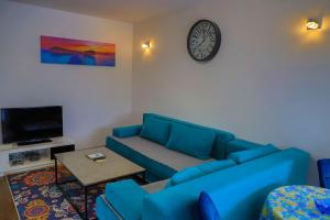 a living room with a blue couch and a clock at Holiday Homes Pozitiva in Bihać +192 photos