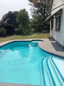 a large blue swimming pool next to a house at Welcoming One Bedroom Flatlet with Pool in Pietermaritzburg