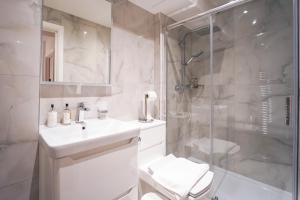 a white bathroom with a sink and a shower at The Avonmore Olympia in London +285 photos