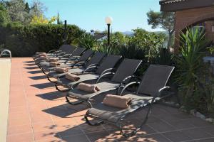 a row of chairs sitting on a patio at Villa Sitges Soledad 15 minutes drive from Sitges XXL swimming pool 12 p in Olivella