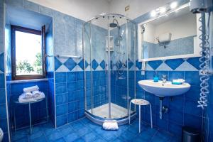 y baño de azulejos azules con ducha y lavamanos. en Sonnino B&B, en Procida