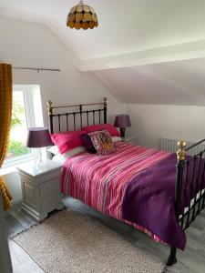 a bedroom with a bed with pink and purple sheets at Katie’s Cottage in Limerick