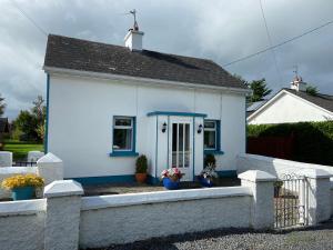 a small white house with a blue roof at Katie’s Cottage in Limerick