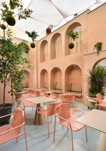 una stanza con tavoli, sedie e piante di Leon's Place Hotel In Rome a Roma