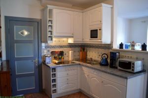 a kitchen with white cabinets and a blue door at Haus 94- Whg EG in Oldsum