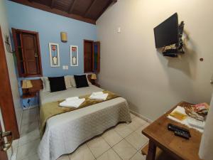 um quarto com uma cama e uma televisão na parede em Pousada Recanto da Grande Paz em Alto Paraíso de Goiás