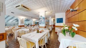 una sala da pranzo con tavoli bianchi e sedie bianche di Hotel Zunino a Spotorno