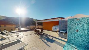 eine Terrasse mit einem Tisch, Stühlen und einem Pool in der Unterkunft Hotel Zunino in Spotorno