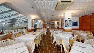 a dining room with white tables and white chairs at Hotel Zunino in Spotorno