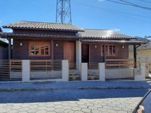 una casa in legno con una recinzione di fronte ad essa di Águia Dourada Hospedagem Casa 01 a Bom Jardim da Serra