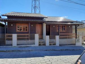 a wooden house with a fence in front of it at Águia Dourada Hospedagem Casa 01 in Bom Jardim da Serra