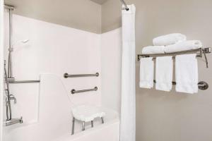 La salle de bains blanche est pourvue d'une douche et de serviettes. dans l'établissement Baymont by Wyndham Whitefish, à Whitefish