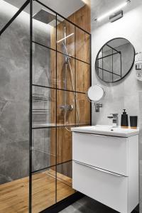 bagno con doccia, lavandino e specchio di HOUSEHOST Apartment :Miodowa 42/4a a Cracovia