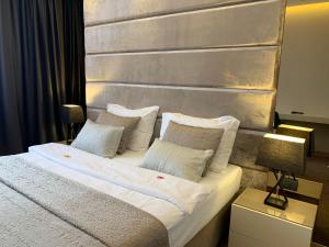 una camera da letto con letto, lenzuola e cuscini bianchi di Hotel Leone a Međugorje