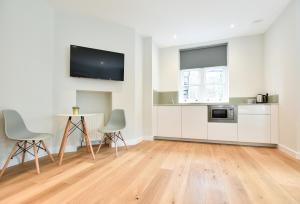 ロンドンにあるSt James House Serviced Apartments by Concept Apartmentsの白いキャビネット、テーブルと椅子付きのキッチンが備わります。