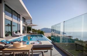 a house with a swimming pool and a patio with a table at Luxury Glass Villas in Syvota