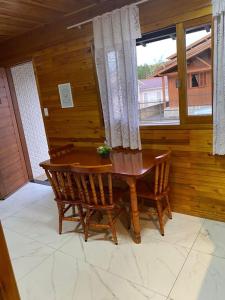einen Holztisch und Stühle in einem Zimmer mit Fenster in der Unterkunft Águia Dourada Hospedagem Casa 01 in Bom Jardim da Serra