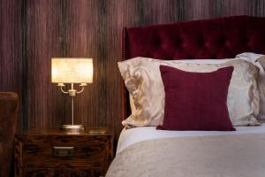uma cama com uma almofada vermelha e um candeeiro numa mesa de cabeceira em The Howbeck & The Retreat incl off-site Health Club and parking EV POINT AVAILABLE em Windermere