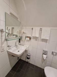a white bathroom with a sink and a toilet at Gasthaus zum Kranz in Lörrach