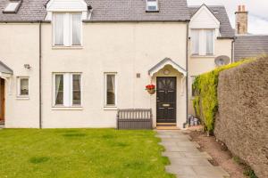 a white brick house with a black door at Abbey Villa Central Boutique House with Parking in St Andrews